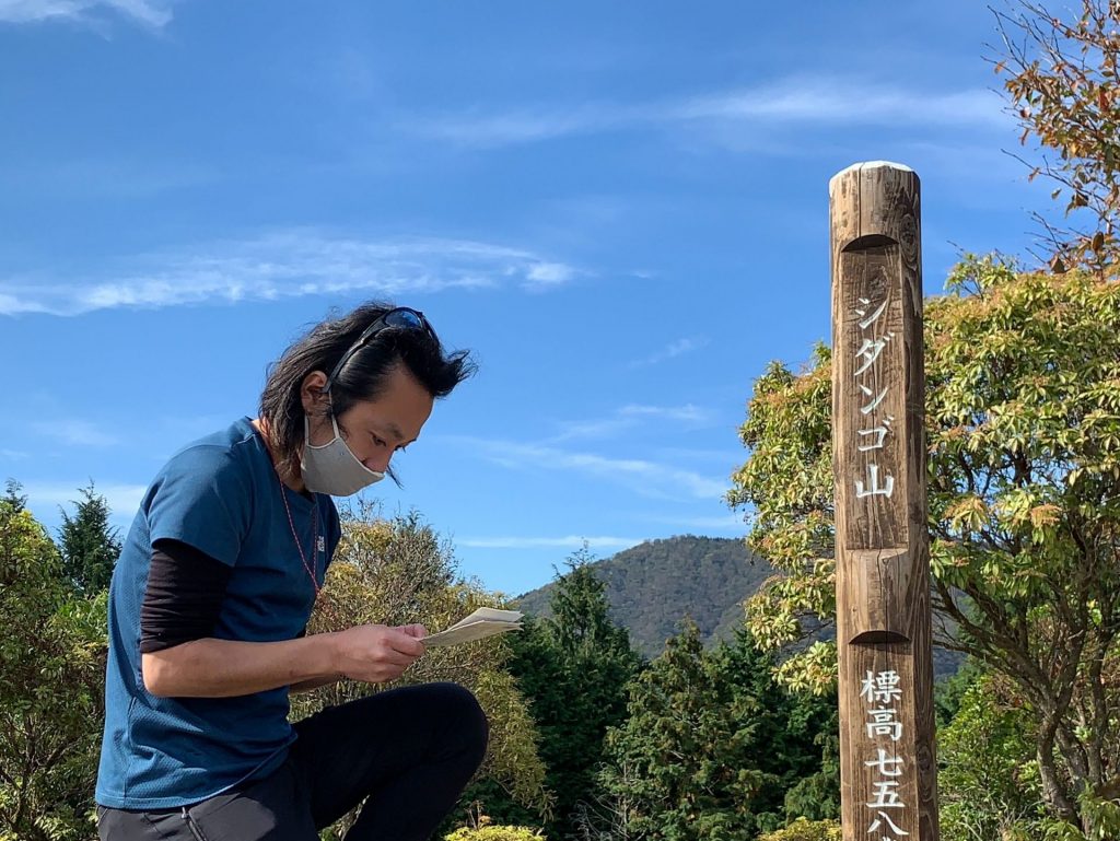 シダンゴ山山頂で地図を確認する鷲尾ガイド