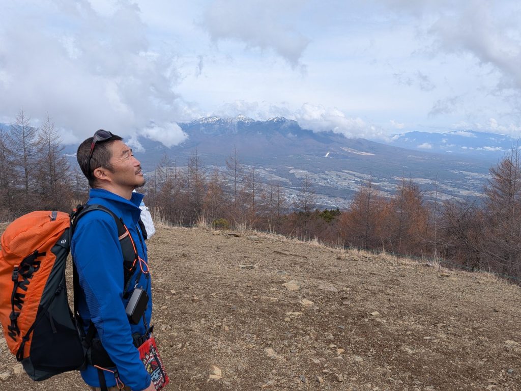 八ヶ岳を背景に雲を眺める猪熊隆之さん